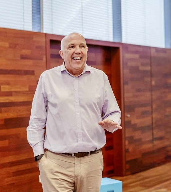 Wayne Jones OBE smiling and speaking to a group in a wood-panelled room